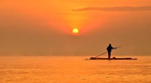 A stand-up rafting fisherman paddles along Lake Victoria in Uganda at sunset. Photo courtesy of Tom McShane Photography. 